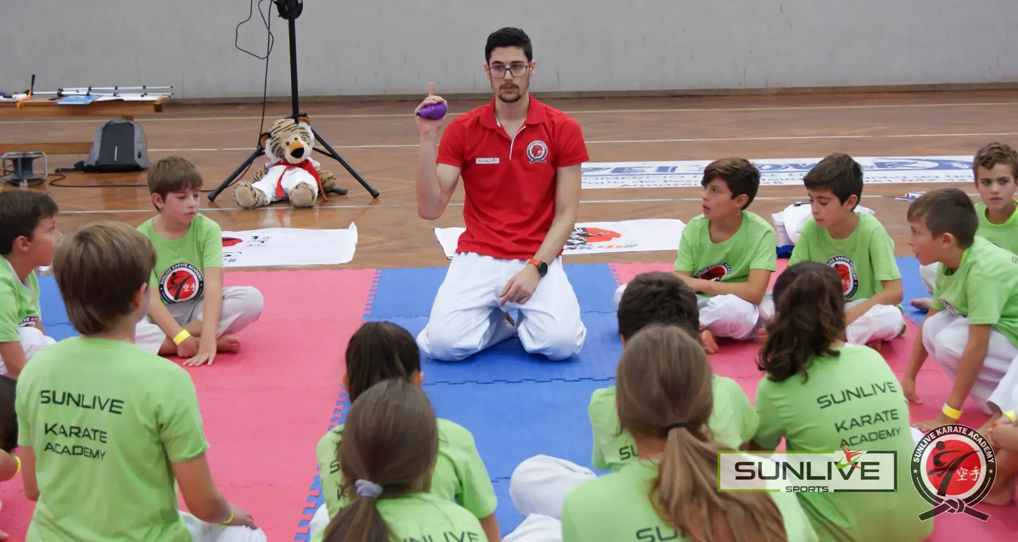 Pedro Miguel fala com crianças sentadas no tatami durante um estágio